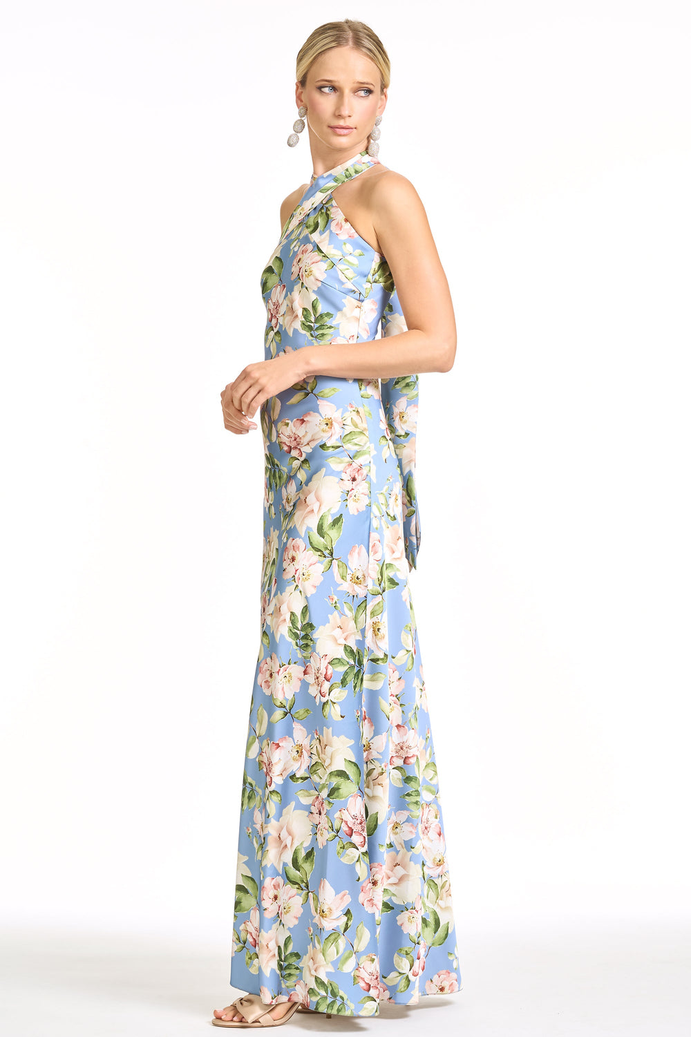 Side view of Laurant gown in Twilight Camellias showcasing halter neckline, fitted hip and flowing full-length skirt on white background