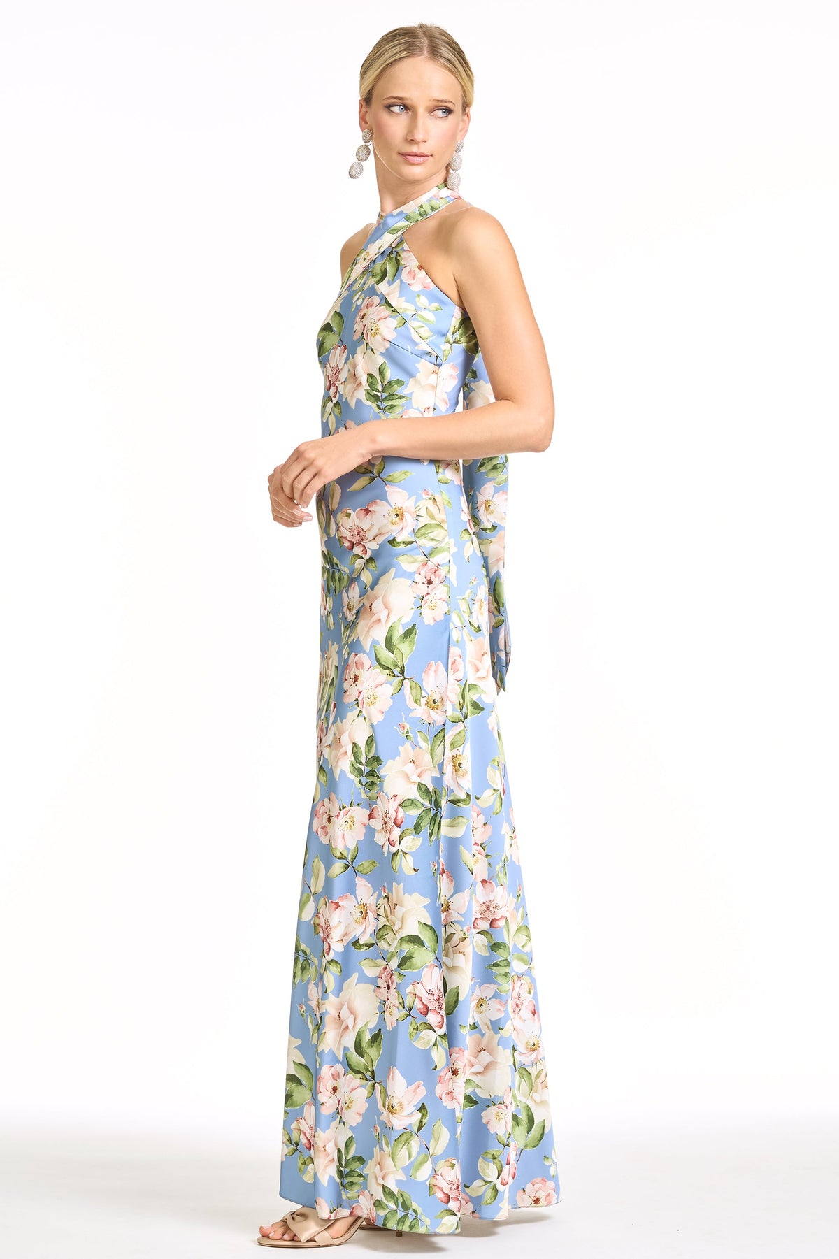 Side view of Laurant gown in Twilight Camellias showcasing halter neckline, fitted hip and flowing full-length skirt on white background