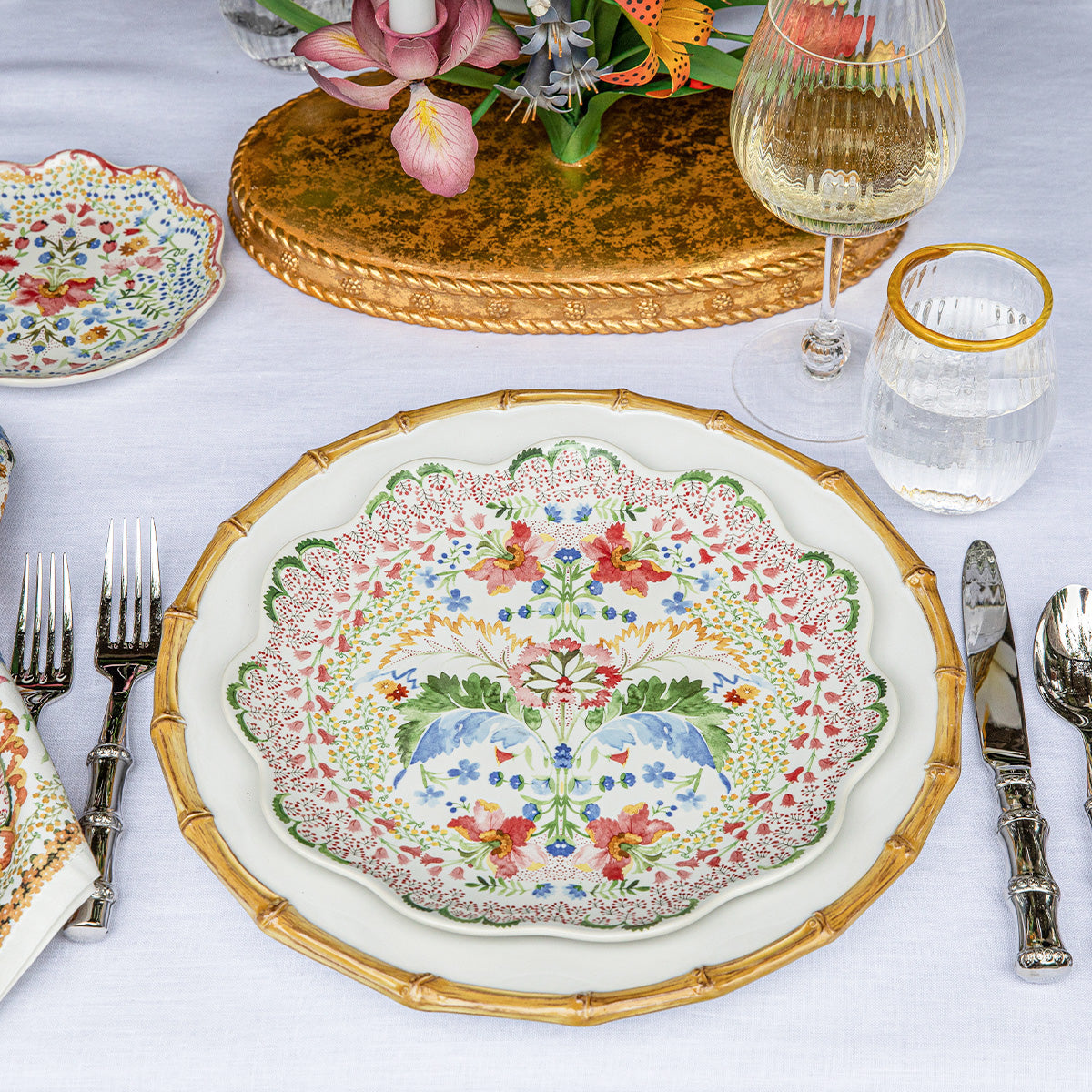 Top view of Sofia dinner plate in Multi showcasing multicolor watercolor floral motif and ruffled rim on white tablecloth