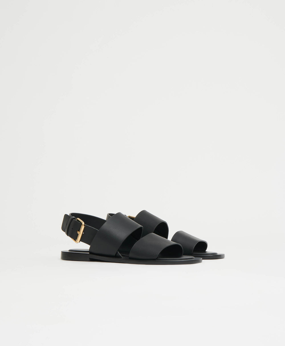 Side view of Double Strap Sandal, black, showing two wide straps, gold buckle back strap and rounded square toe on white