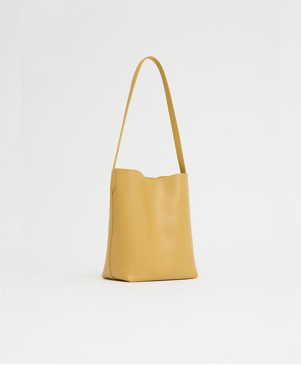 Three-quarter view of Small Everyday Cabas in Paglia showcasing slouchy silhouette and long shoulder strap on white background