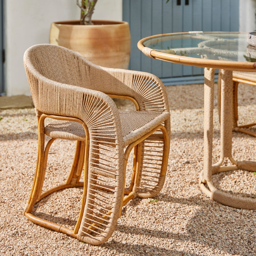 Three-quarter view of Glen Ellen Indoor and Outdoor arm chair showcasing woven rattan wrapped with performance rush on a gravel patio