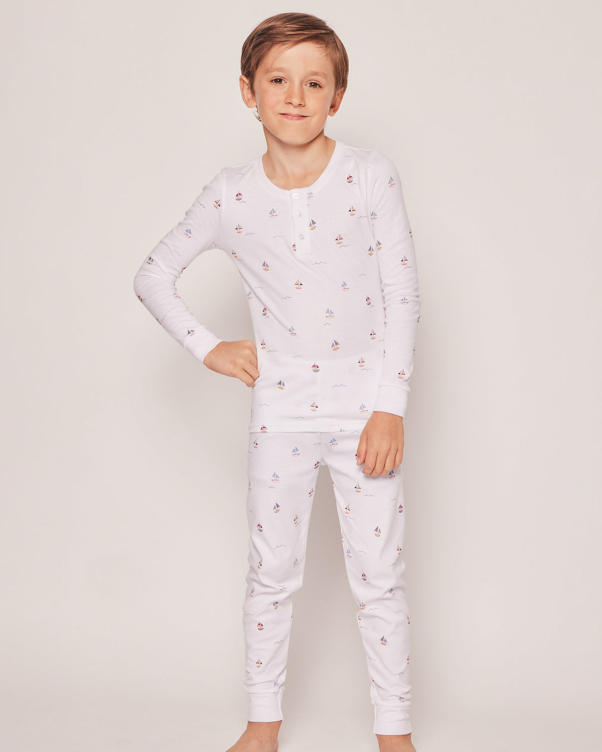 Front view of Kid’s Pima Snug Fit Pajama Set in Bateau showcasing sailboat print on a child against a light background