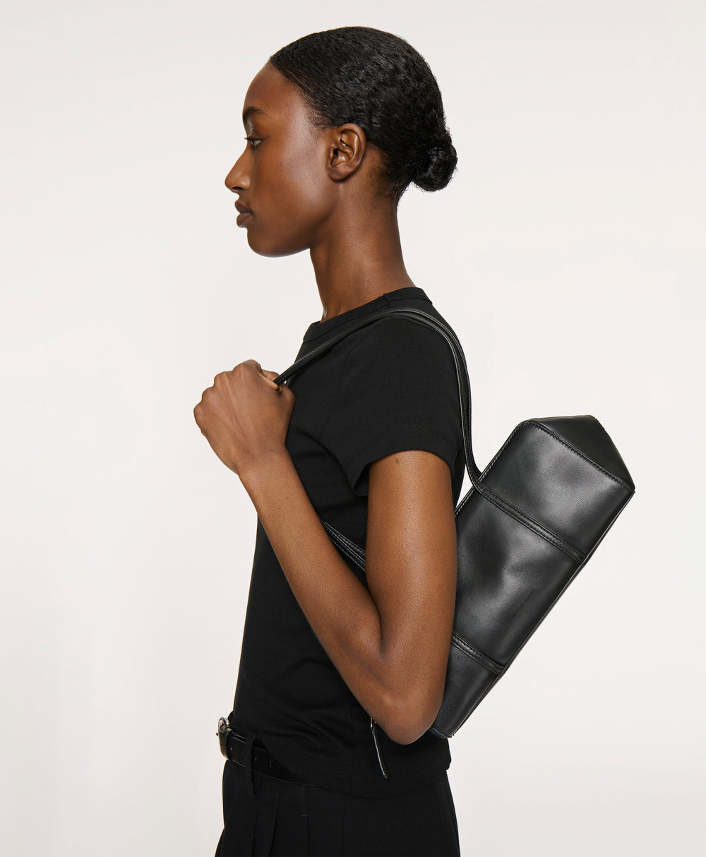 Side view of Filo Bag in black on model showing soft rectangular shape and thin double shoulder straps against a plain light background