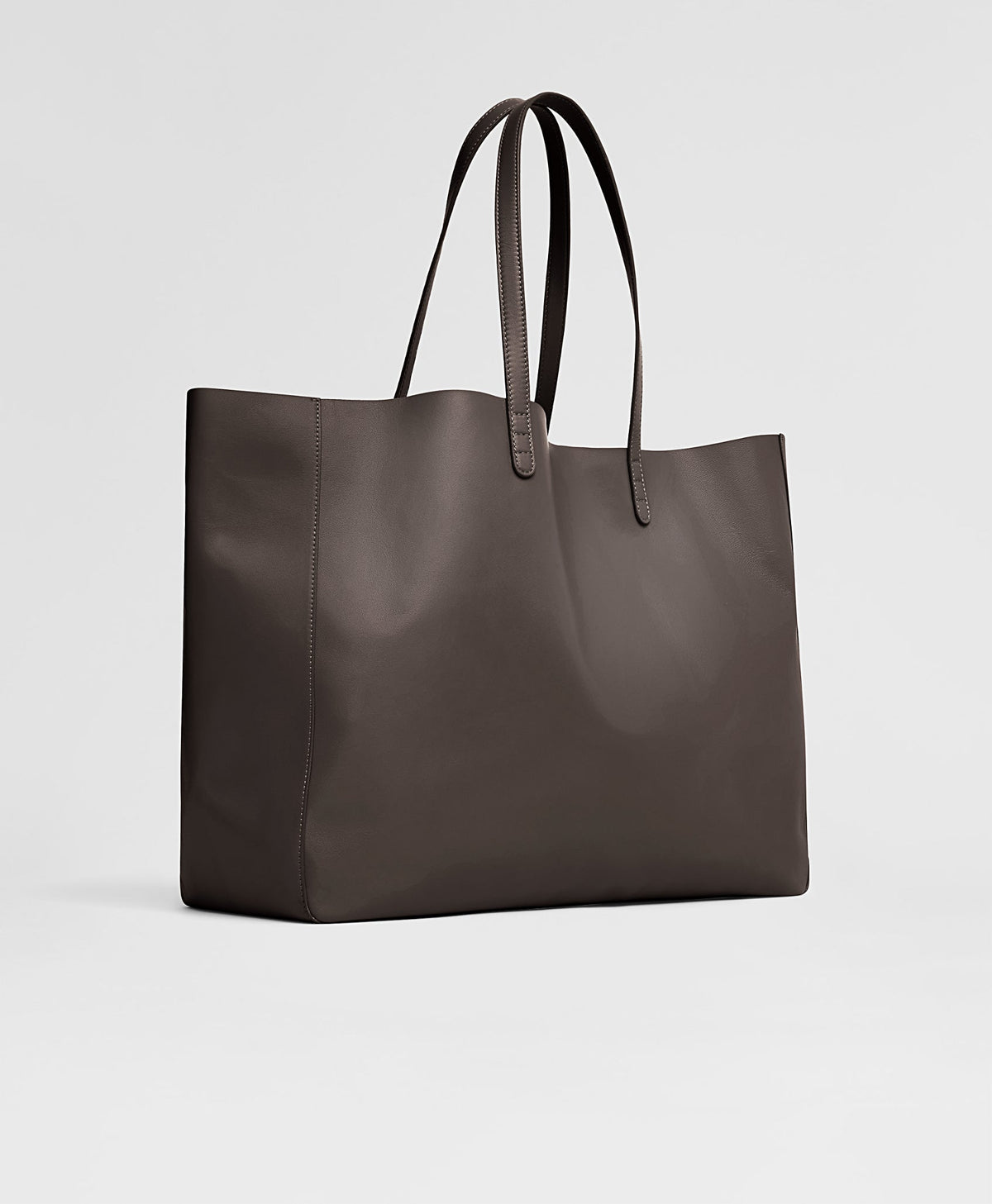 Angled view of Juno Tote in Ebony showing oversized lambskin silhouette and shoulder straps on light gray background