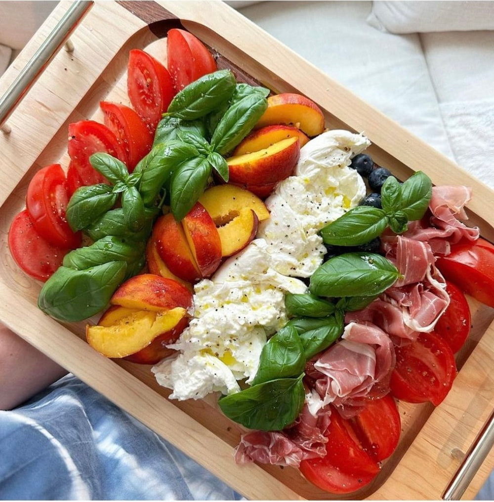 Top view of Rod Handle Steak Board showcasing stainless steel rod handles and juice groove with fresh tomatoes and burrata