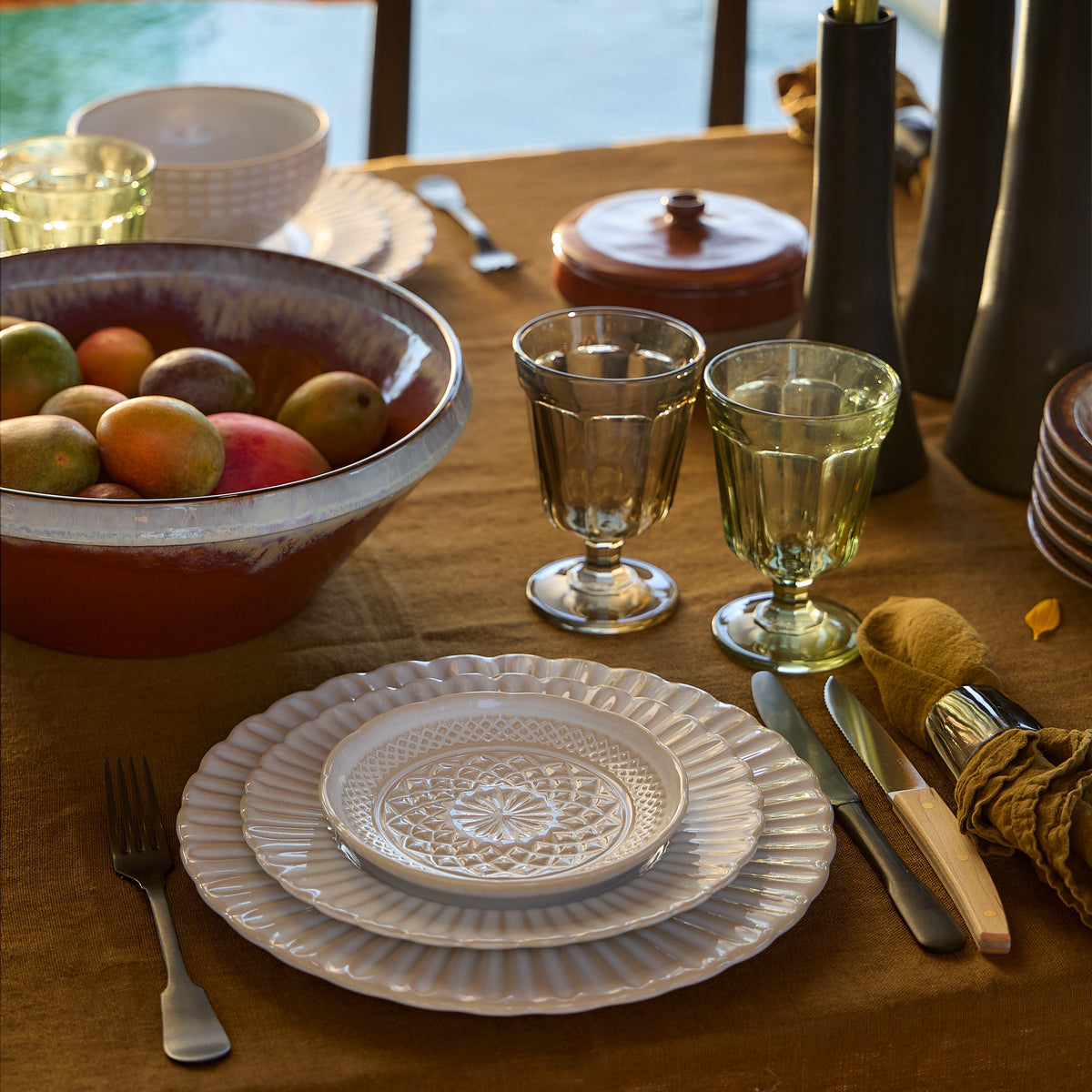 Front view of Cristal Collection white dinner plates stacked to show embossed crystal pattern on rust-brown linen table