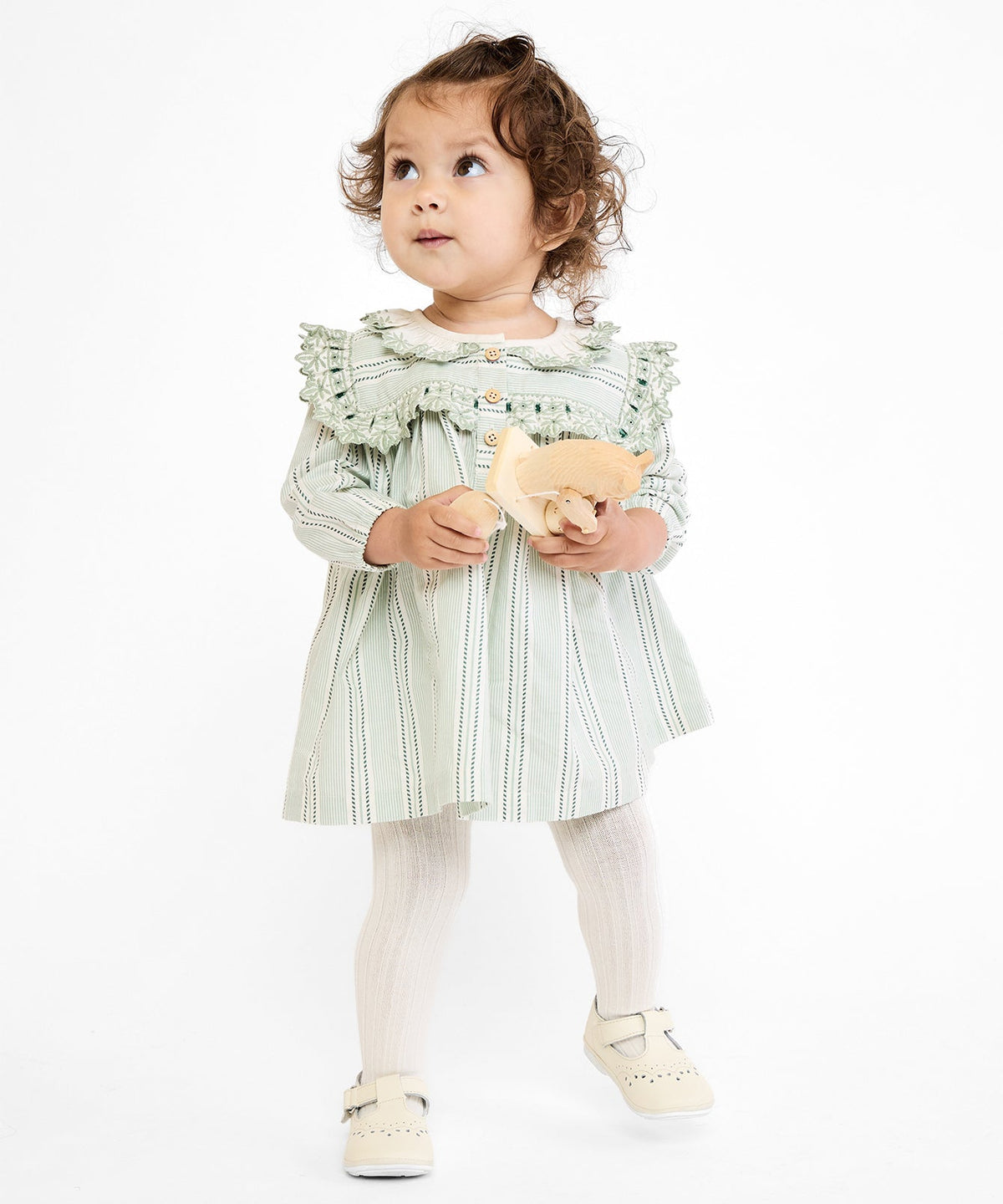 Front view of sage chevron stripe Sara baby dress on toddler model, showing embroidered yoke and collar