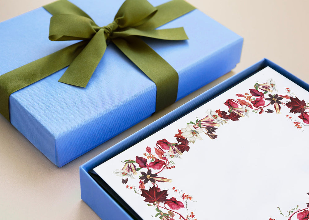 Scarlet Maple stationery in open blue gift box displaying red floral maple-leaf border and olive-green ribbon