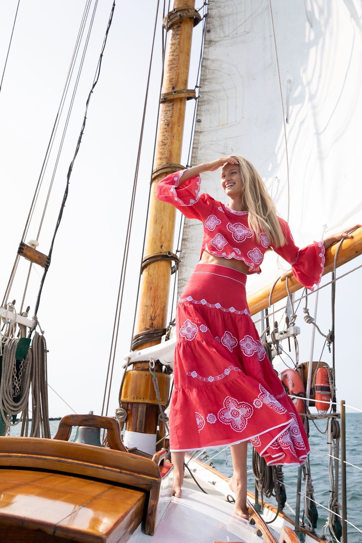 Three-quarter view of Scarlet Willow tiered skirt on model showing clover embroidery and scalloped hem on a sailboat deck