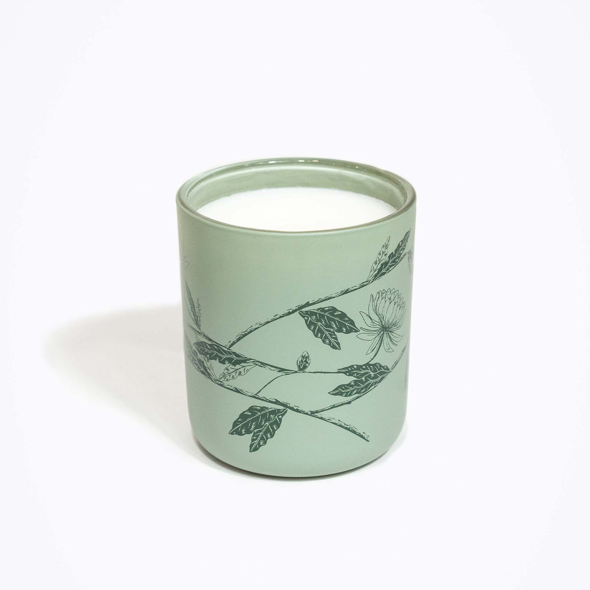 Front view of Moorland Breeze candle showing a light green ceramic jar with dark botanical print on white background