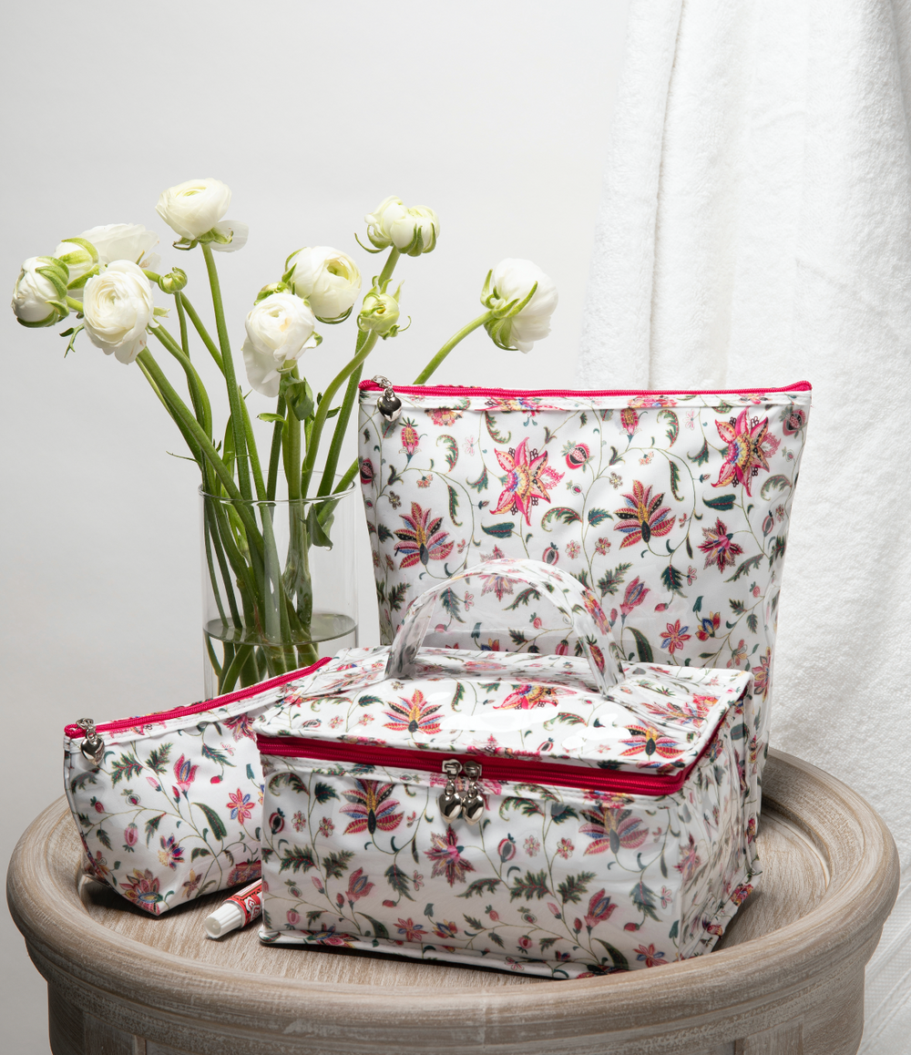 Front view of small Jacaranda Living cosmetic bag with pink zipper and heart pull on wooden pedestal with matching pouches