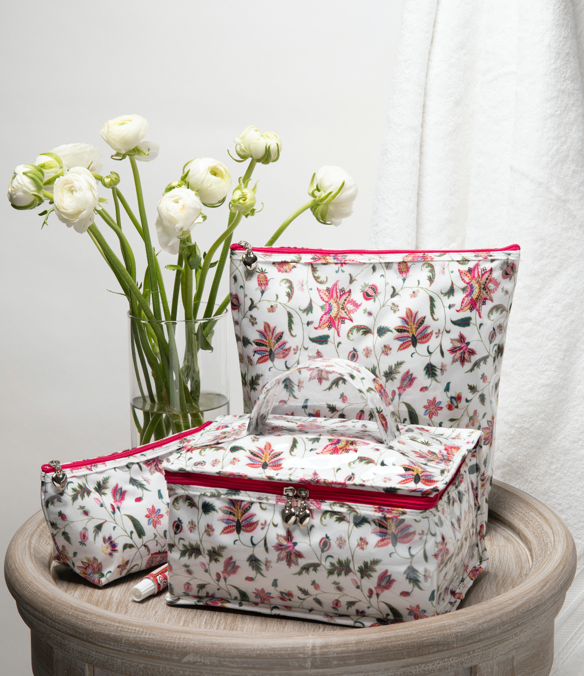 Front view of small Jacaranda Living cosmetic bag with pink zipper and heart pull on wooden pedestal with matching pouches