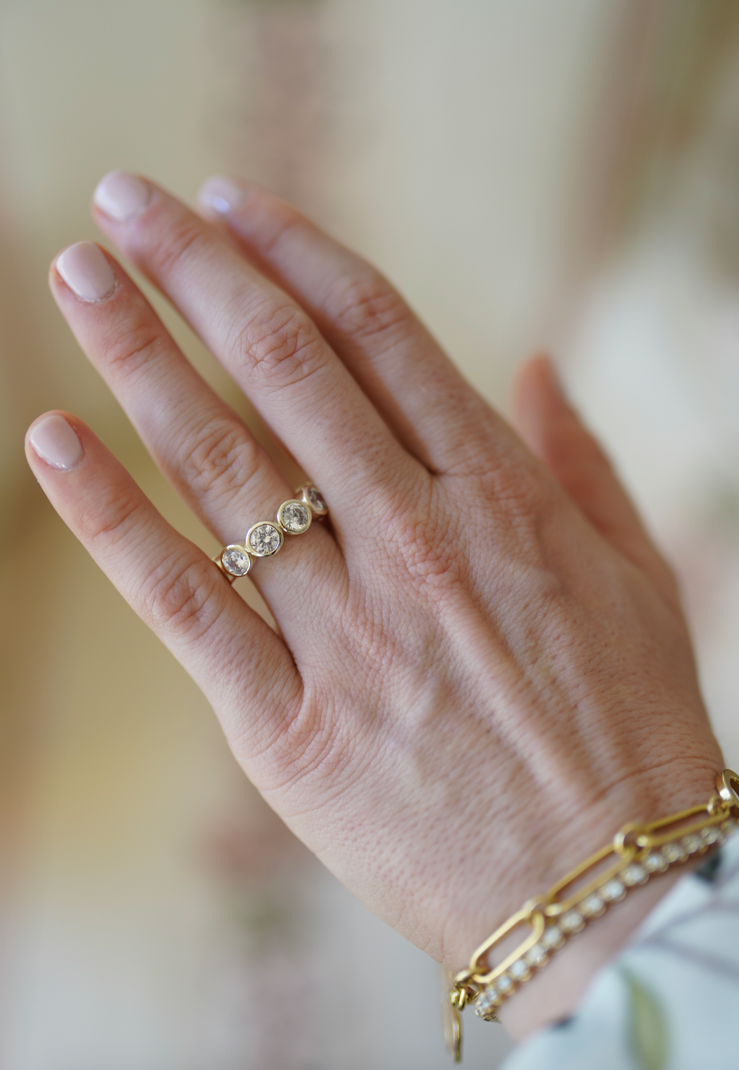 Close-up of the Grand Blanc Bezel Band showcasing its delicate gold-plated bezel design on a hand with a blurred background