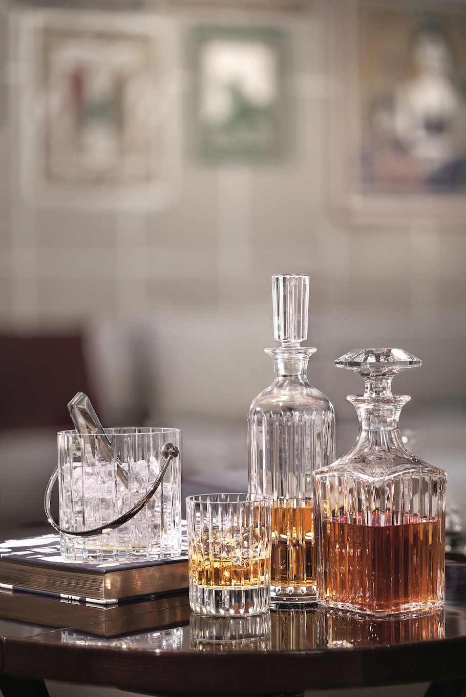 Front view of Baccarat Harmonie tumblers, decanters, and ice bucket showcasing vertical parallel cuts in clear crystal on a wooden table