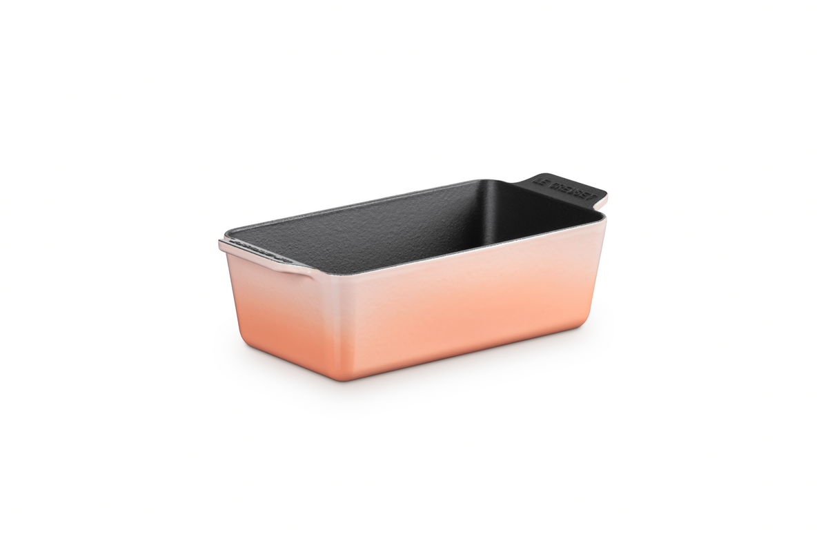 Three quarter view of Signature Loaf Pan in Peche showcasing its black interior and side handles on a white background