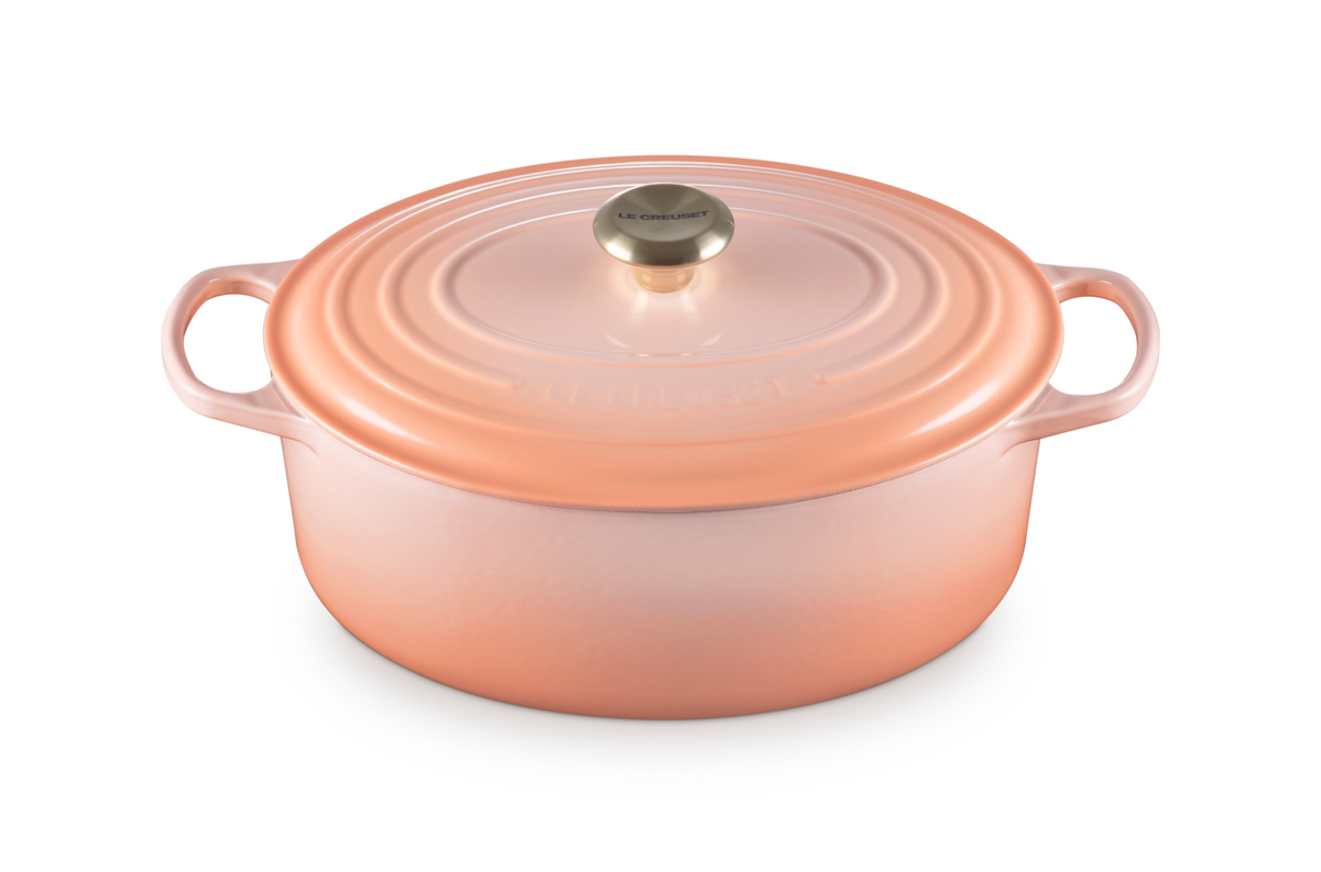 Front view of Signature Oval Dutch Oven 6.75 qt in Peche showcasing matching lid and side handles on a white background