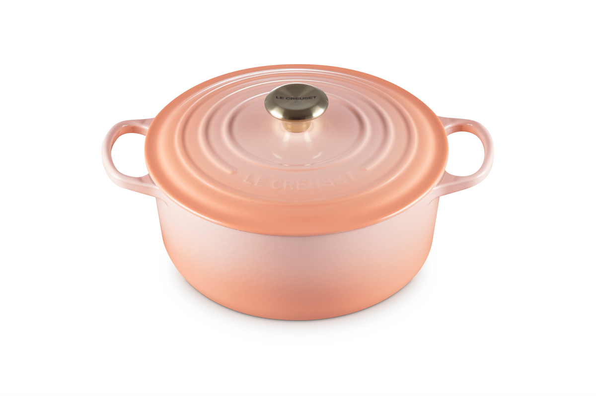 Front view of Signature Round Dutch Oven in Peche showcasing wide loop handles and stainless steel knob on white background