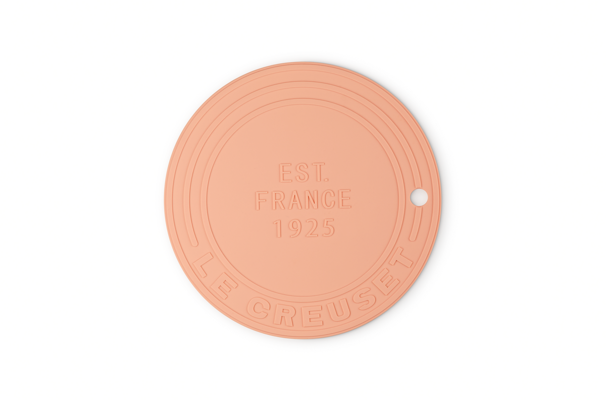 Front view of Silicone Trivet in Peche showcasing round design, hanging hole, and raised EST. FRANCE 1925 lettering