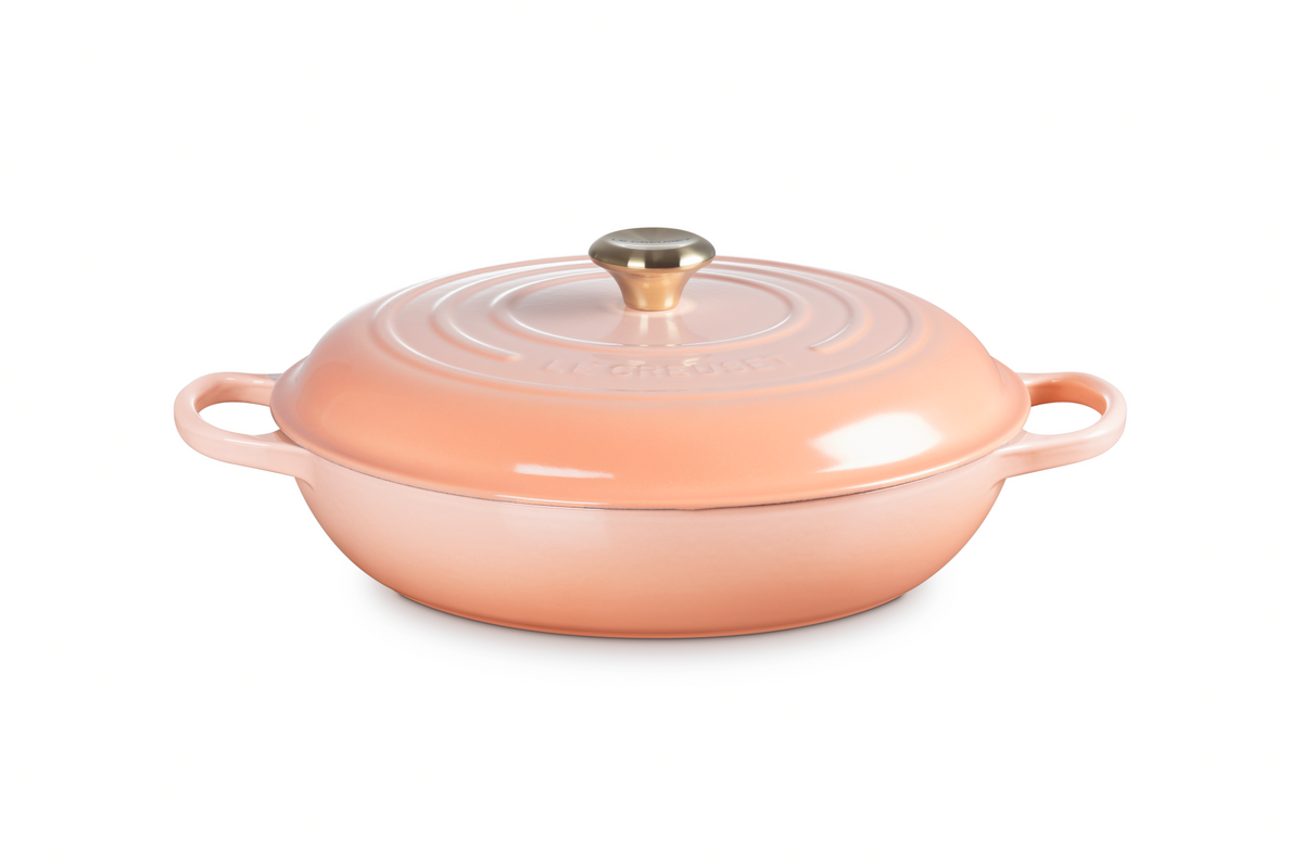Front three quarter view of Signature Braiser in Peche showcasing domed lid and wide loop handles with white background