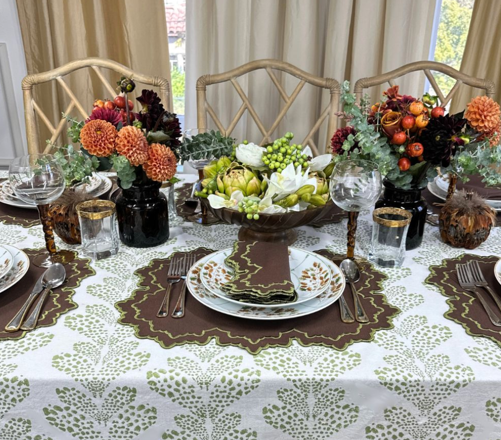 Brown embroidered napkins arranged on a decorated dining table with floral centerpieces and place settings
