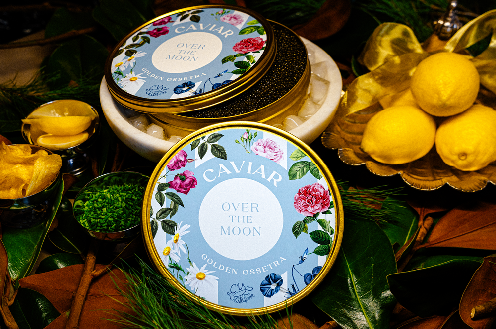 Close up of Over The Moon Golden Ossetra caviar tin open to show black pearls on ice with lemons and chives