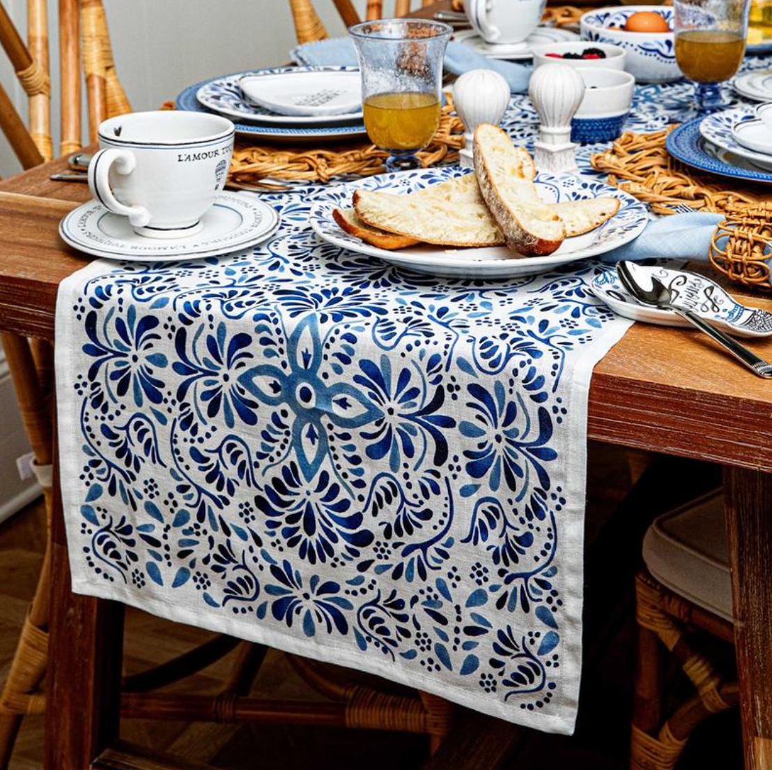 Front view of Iberian 18 by 90 inch table runner in Indigo showcasing a cobalt blue floral pattern on white linen with a set dining table