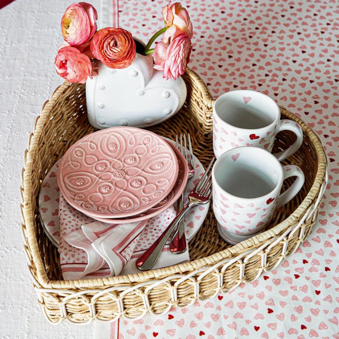Top view of Jardins Du Monde blush side plates showing embossed floral design in a wicker heart basket with heart-print napkin and mugs