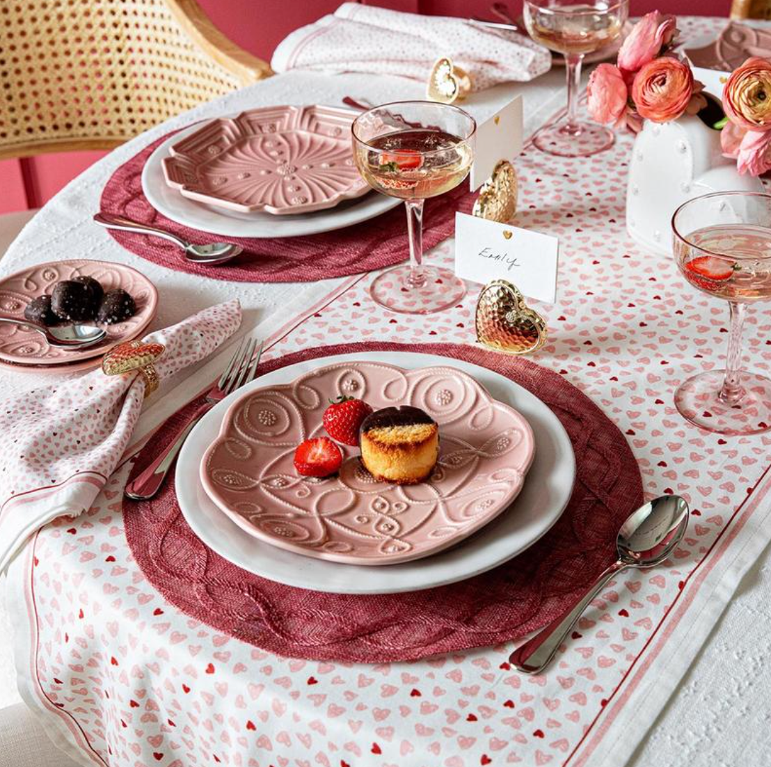 Close-up of assorted blush Jardins Du Monde dessert plates with raised garden-inspired patterns on a heart-print table