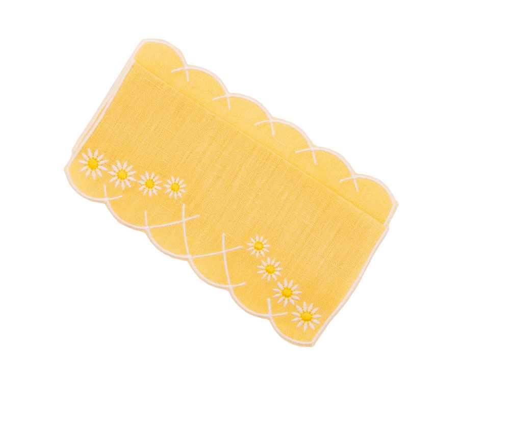 Flat lay of Daisy Aperitivo cocktail napkin in yellow showing embroidered daisy motifs and scalloped edge on white background