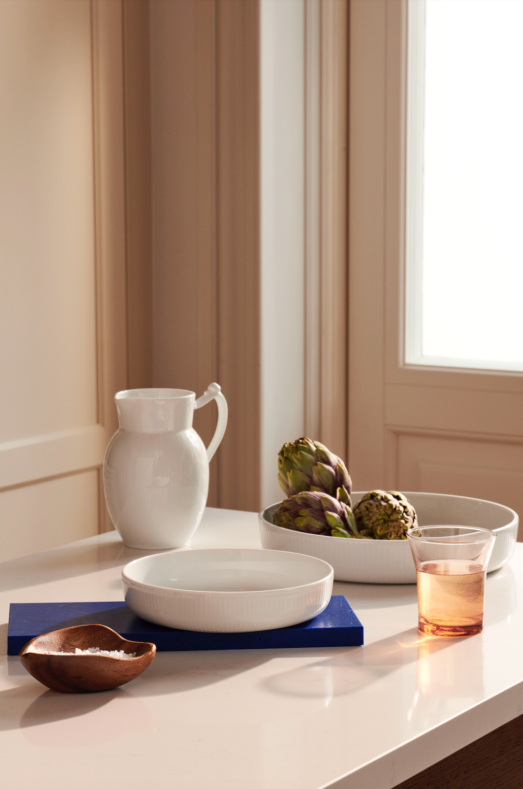 Angled view of White Fluted Ovenware Round showcasing its fluted porcelain rim on a kitchen counter
