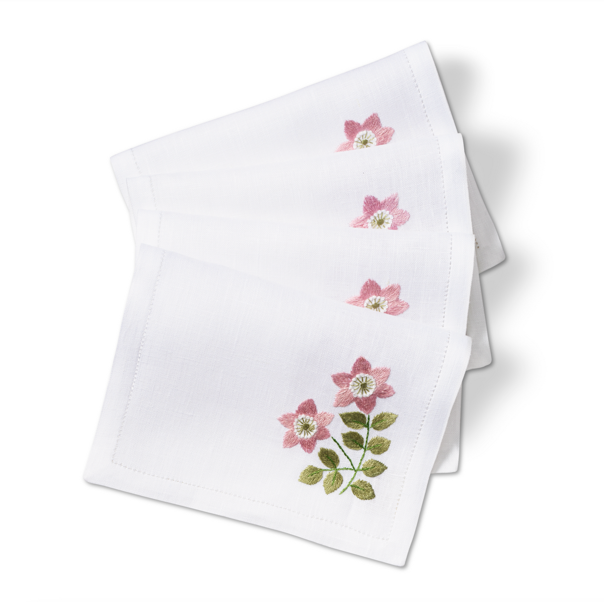 Angled view of Wild Flower Embroidered Cocktail Napkins, Set of 4 showcasing pink wildflower embroidery on white linen with a white background