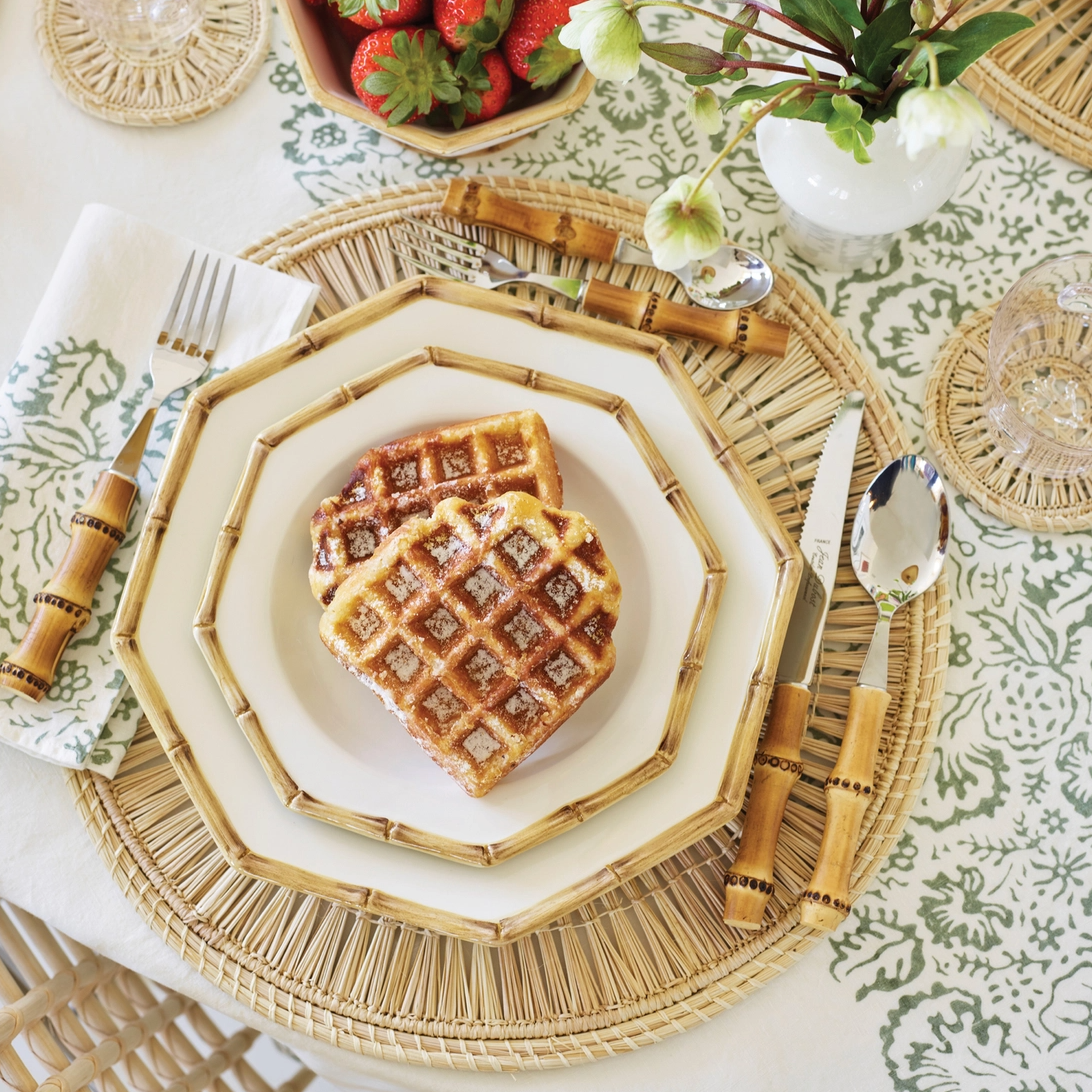 Ada raffia coasters used as placemats under bamboo-rimmed plates with waffles and bamboo utensils on patterned tablecloth