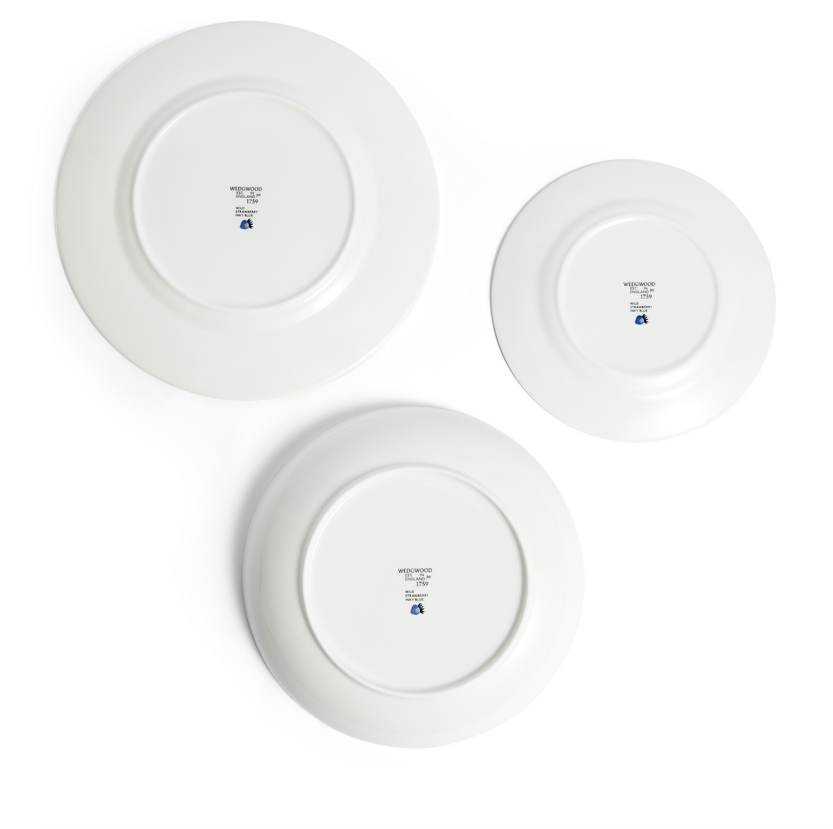 Overhead view of three upside-down Wild Strawberry Inky Blue bone china plates showing Wedgwood backstamp on white background