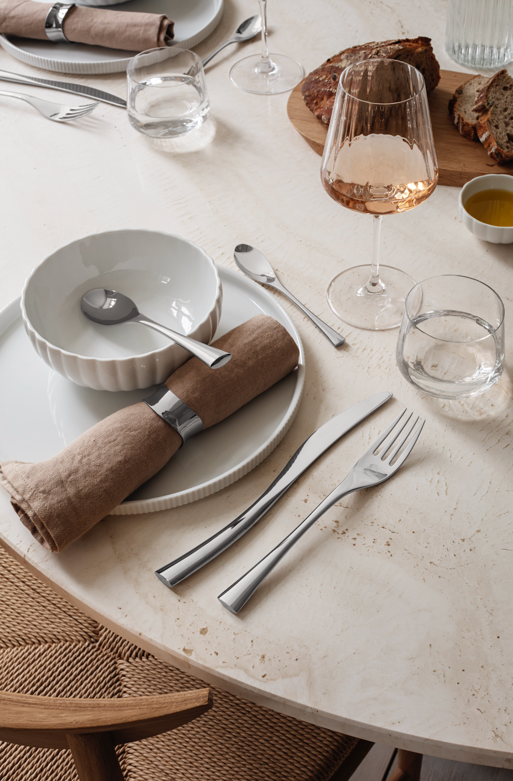 Angled view of Bernadotte Breakfast Bowl Porcelain showcasing ridged sides with tableware on a dining table