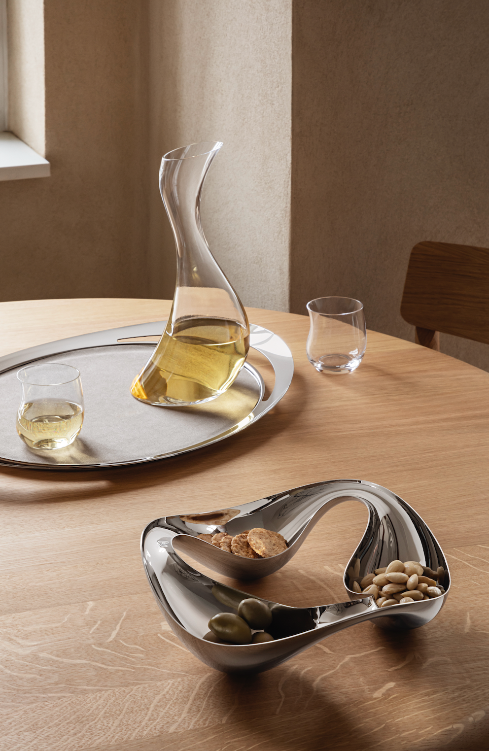 Angled view of Cobra Triple Snack Bowl showing three sections and mirror-polished stainless steel on a table