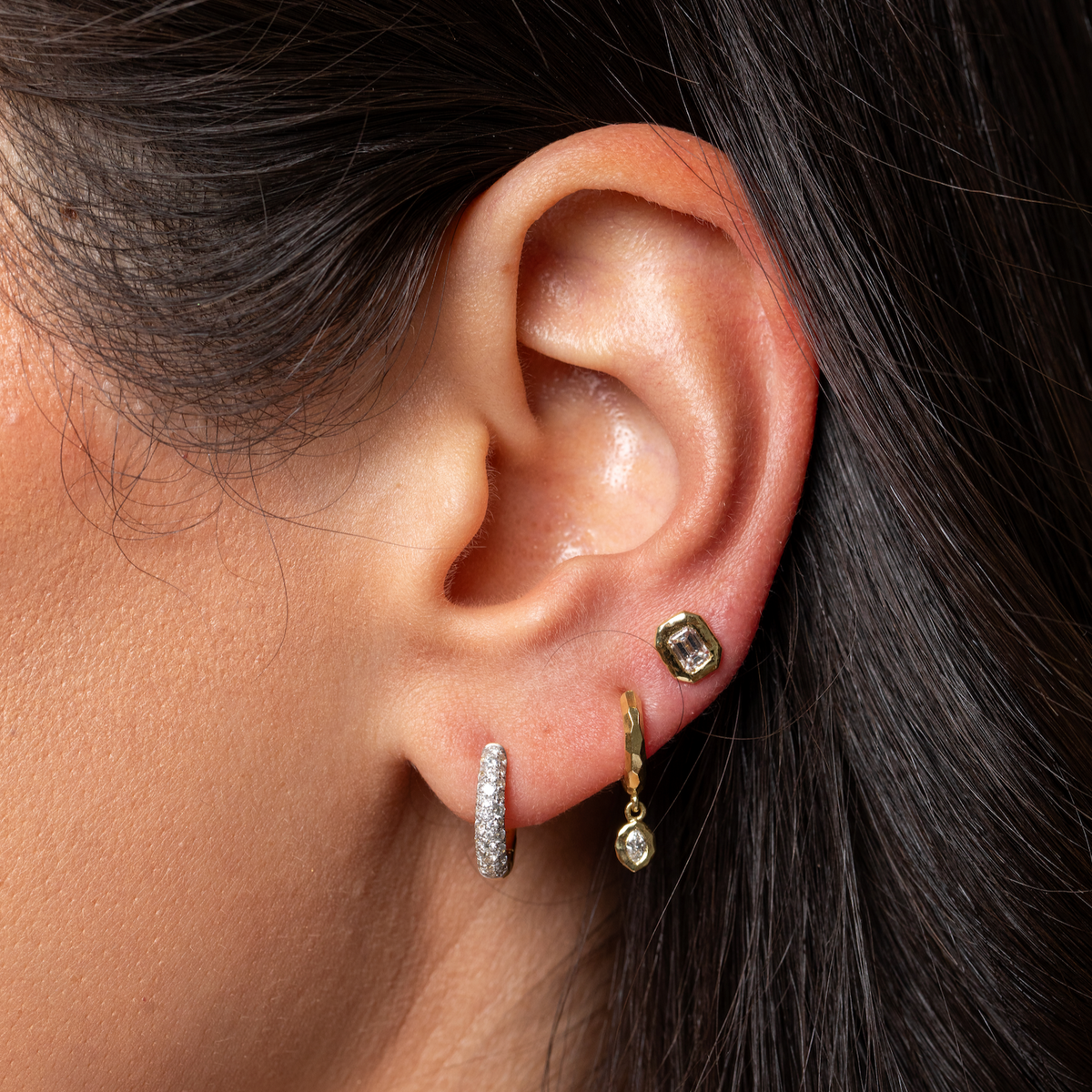 Close-up of Cobblestone Petite Diamond Hoop on a model’s ear showcasing pave-set micro diamonds against dark hair