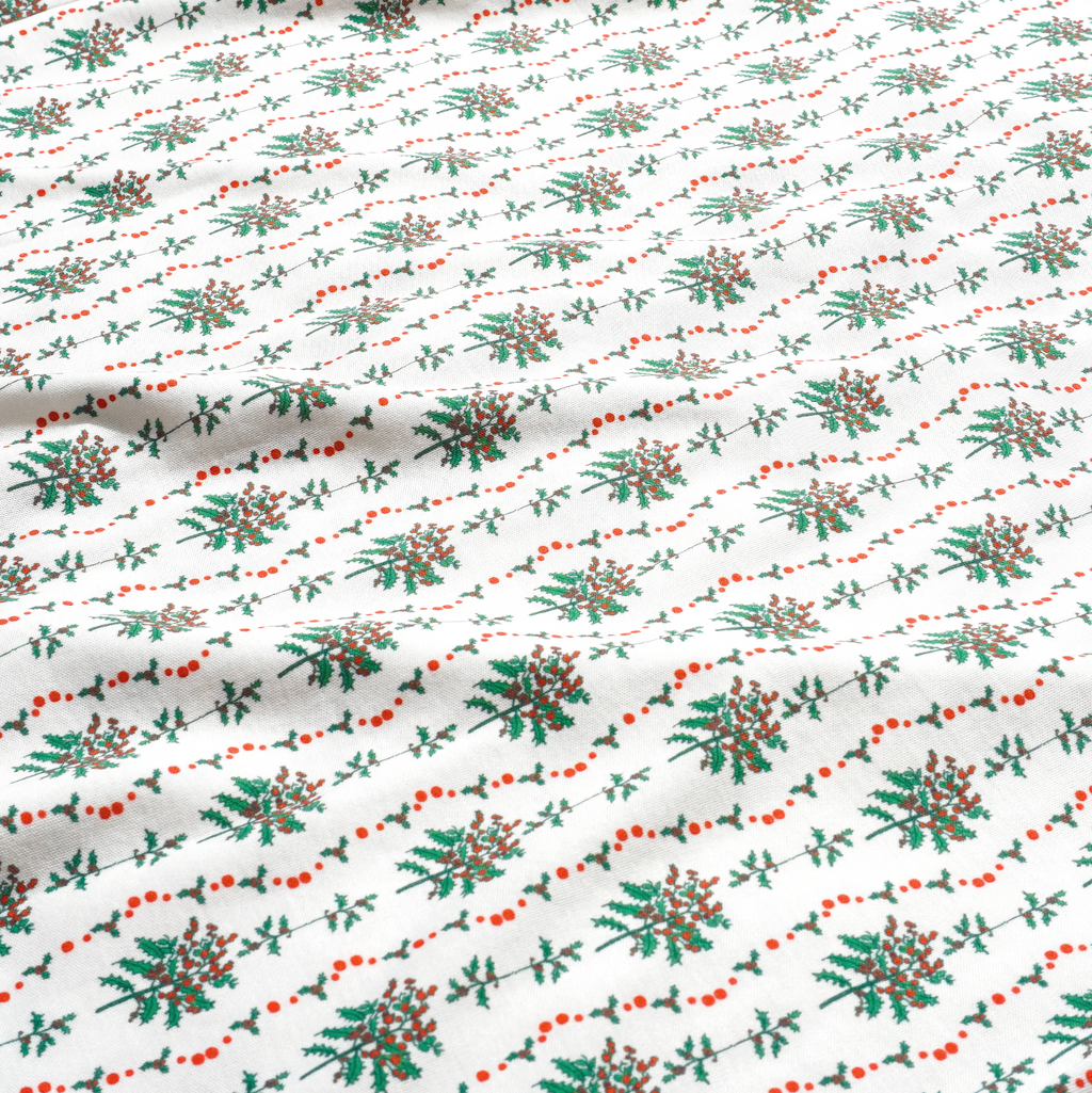 Close-up of Holly Baby Snap Onesie showcasing hand-drawn greenery and red berry print on white fabric