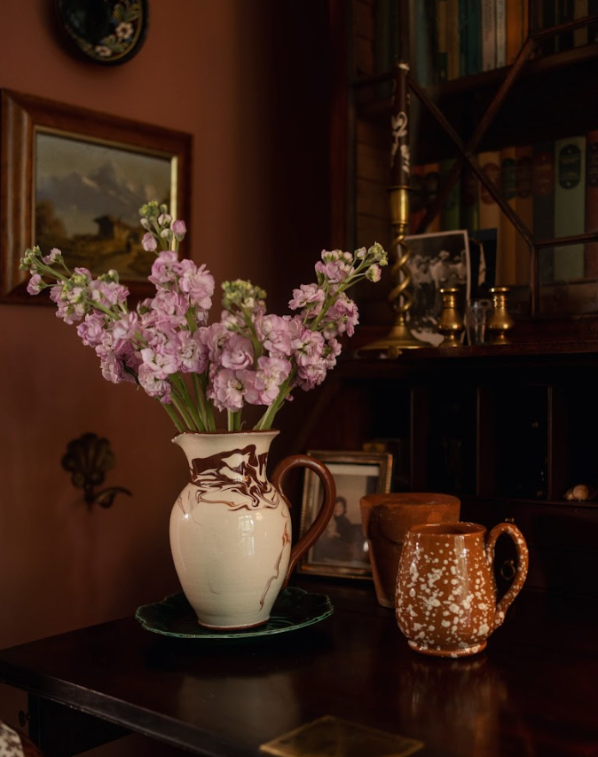Three-quarter view of Splatter Mug in terracotta and cream with speckled glaze and curved handle on a wood table