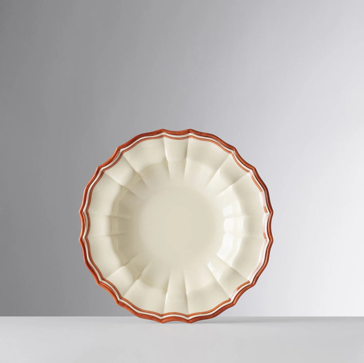 Top view of Eva acrylic bowl showing scalloped edges and rust-orange rim on light gray background