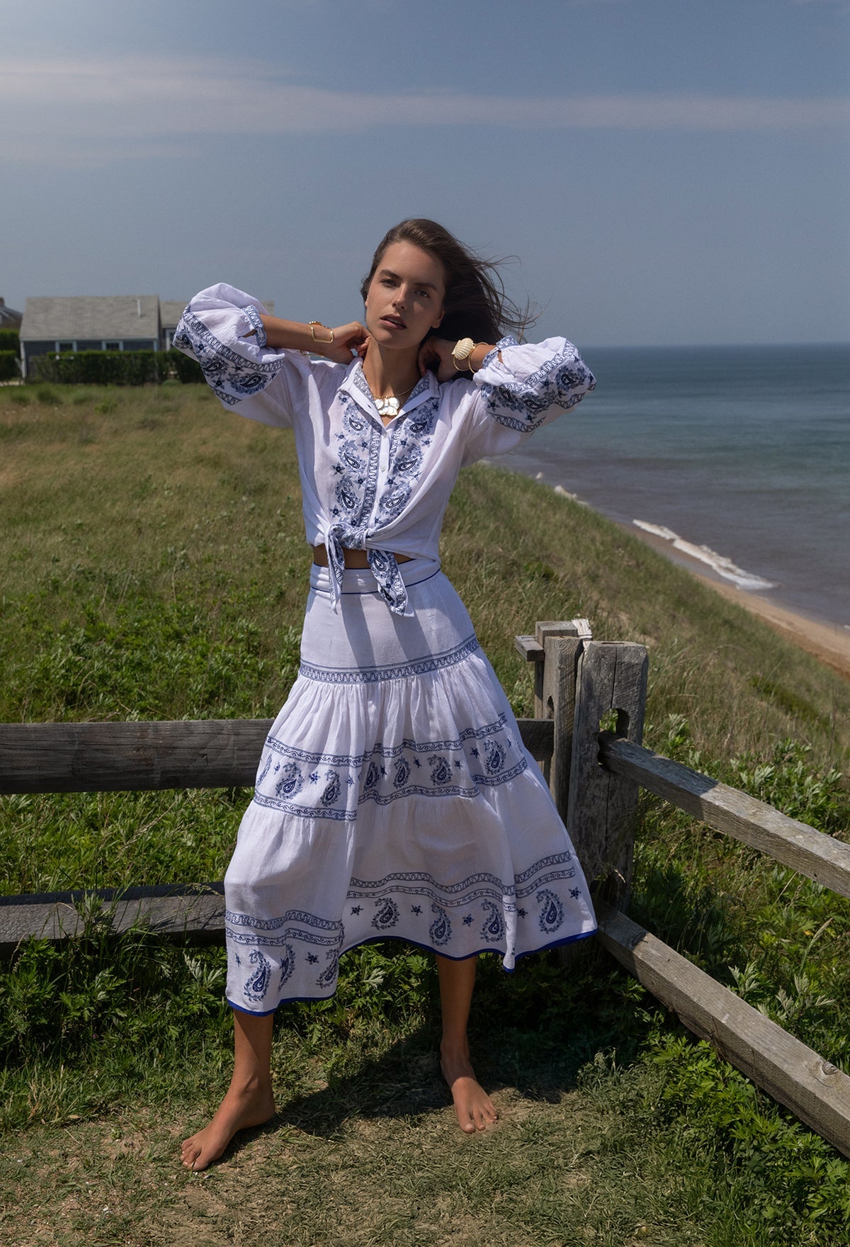 Front view of Seaside Blaire Blouse showcasing tied front, blue paisley embroidery and billowed sleeves with coastal bluff background