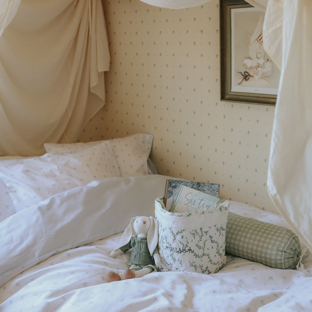 Bedroom with a bed featuring pillows and a teddy bear, decorated with a framed picture on the wall.