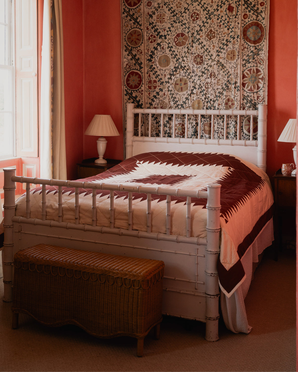 Angled view of Maurier Quilt on a white bed showing burgundy and cream starburst patchwork and hand-stitched cotton