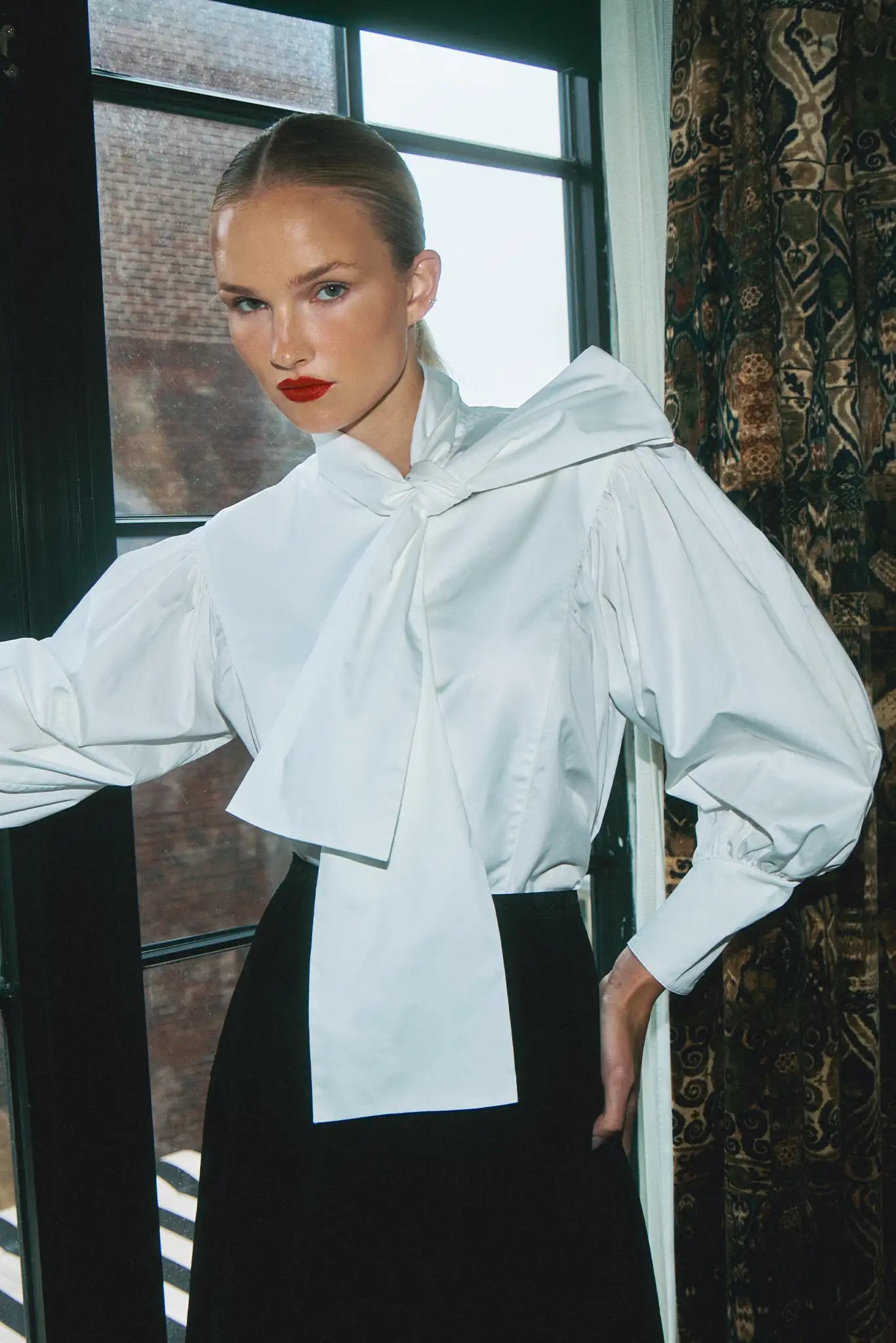 The Shay Blouse is designed with a tie-front neckline and long sleeves with angled button cuffs