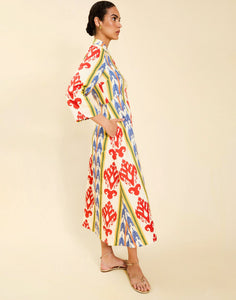Woman wearing the Mestiza Shoshi Midi Dress in Ikat Sunrise print, featuring a fitted bodice, A-line midi skirt, mandarin collar, functional frog tie closures, side seam pockets, and linen fabrication.