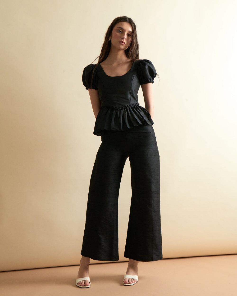 Front view of Libby Pant in Noir on model showing high waist, wide cropped legs and dupioni fabric against beige background