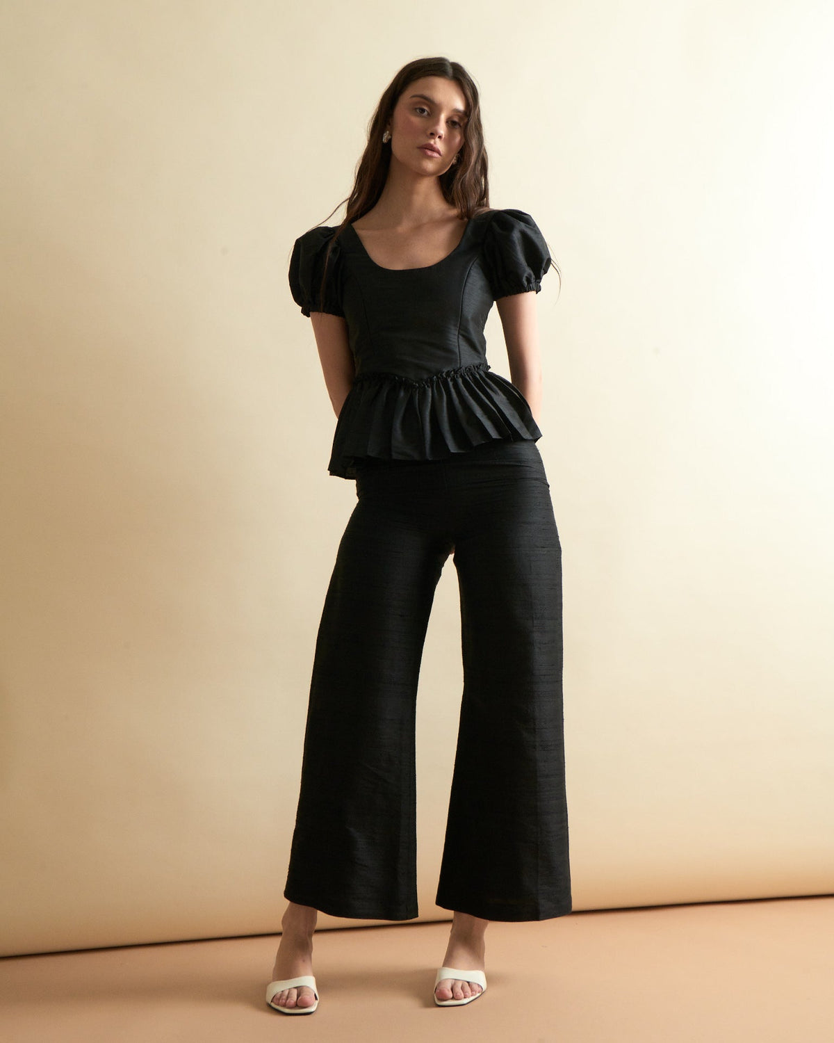 Front view of Libby Pant in Noir on model showing high waist, wide cropped legs and dupioni fabric against beige background