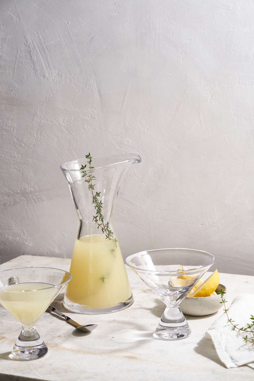 Front view of Westport Bar Gift Set with quartino carafe, two martini glasses, and stirring spoon on light tabletop