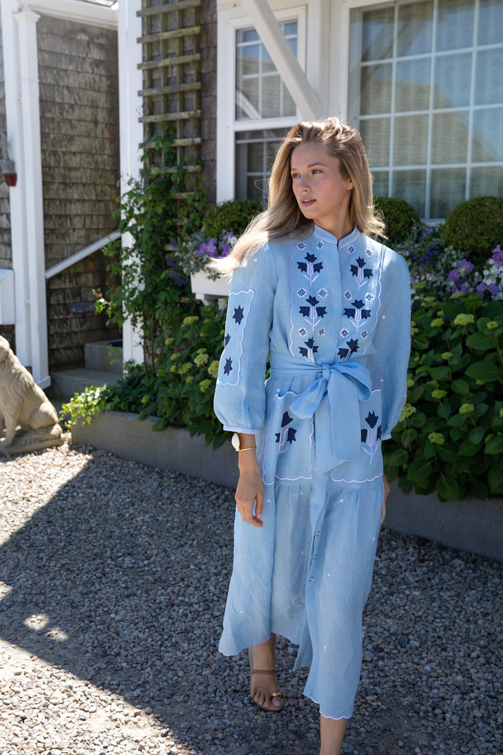 Three-quarter view of Sky Kingsley dress showing light-blue linen, embroidered stars and tulips, puff sleeves, scalloped hem, tie belt and pockets