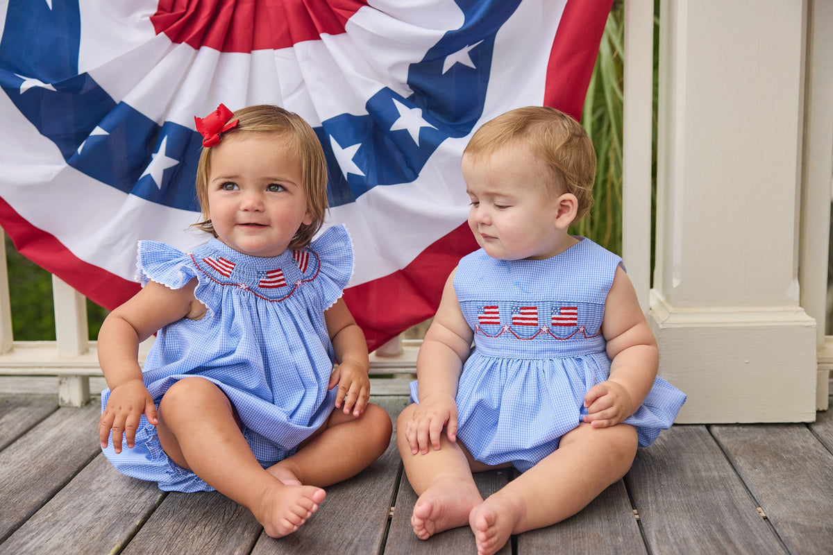 Little English traditional children's clothing.  Sleeveless bubble in royal blue mini check fabric and smocking at the chest with American flag bunting for baby boys